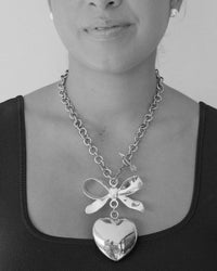 model wears a large necklace with a heart abnd bow and arrow clasp