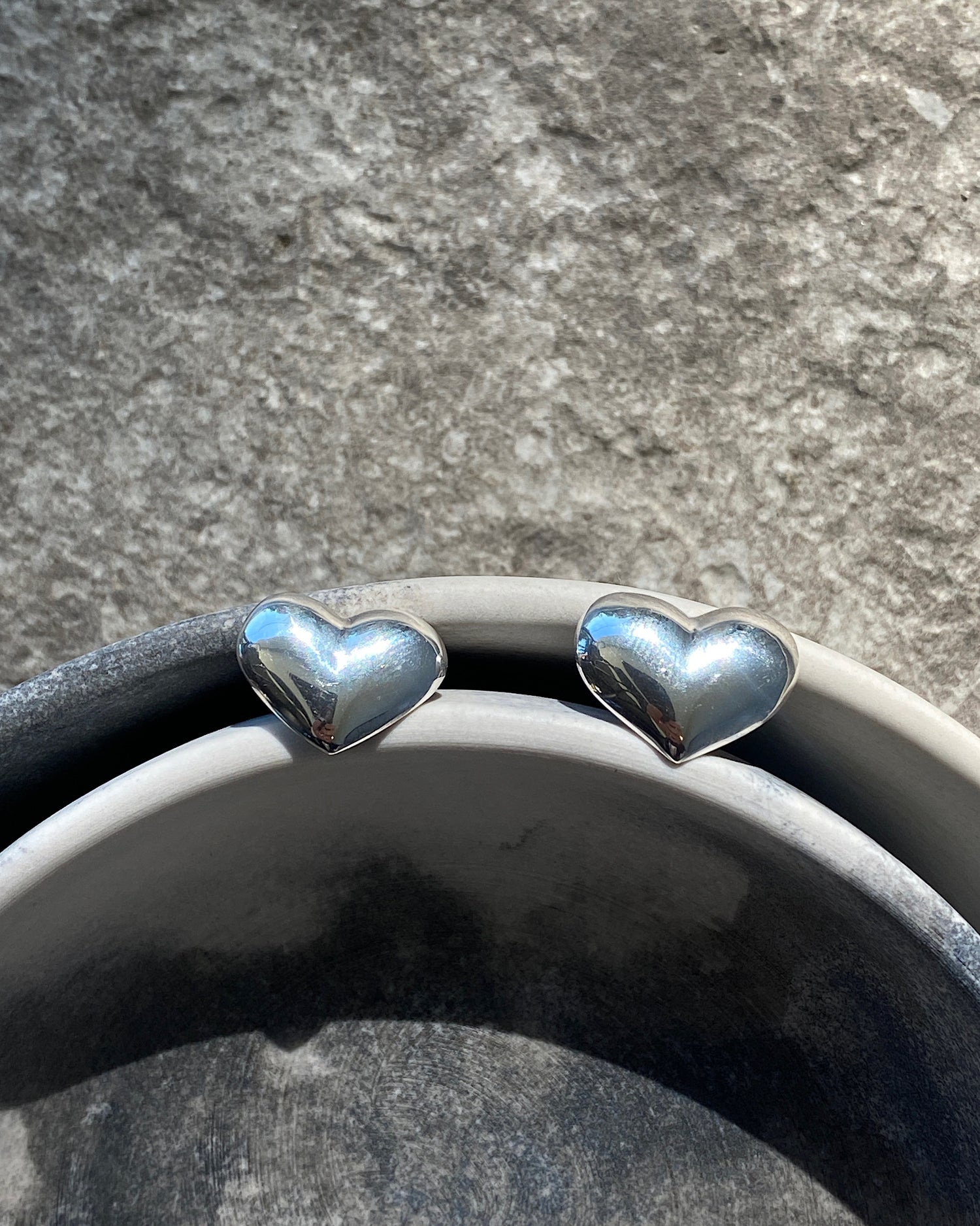 silver heart earrings sit in bowls