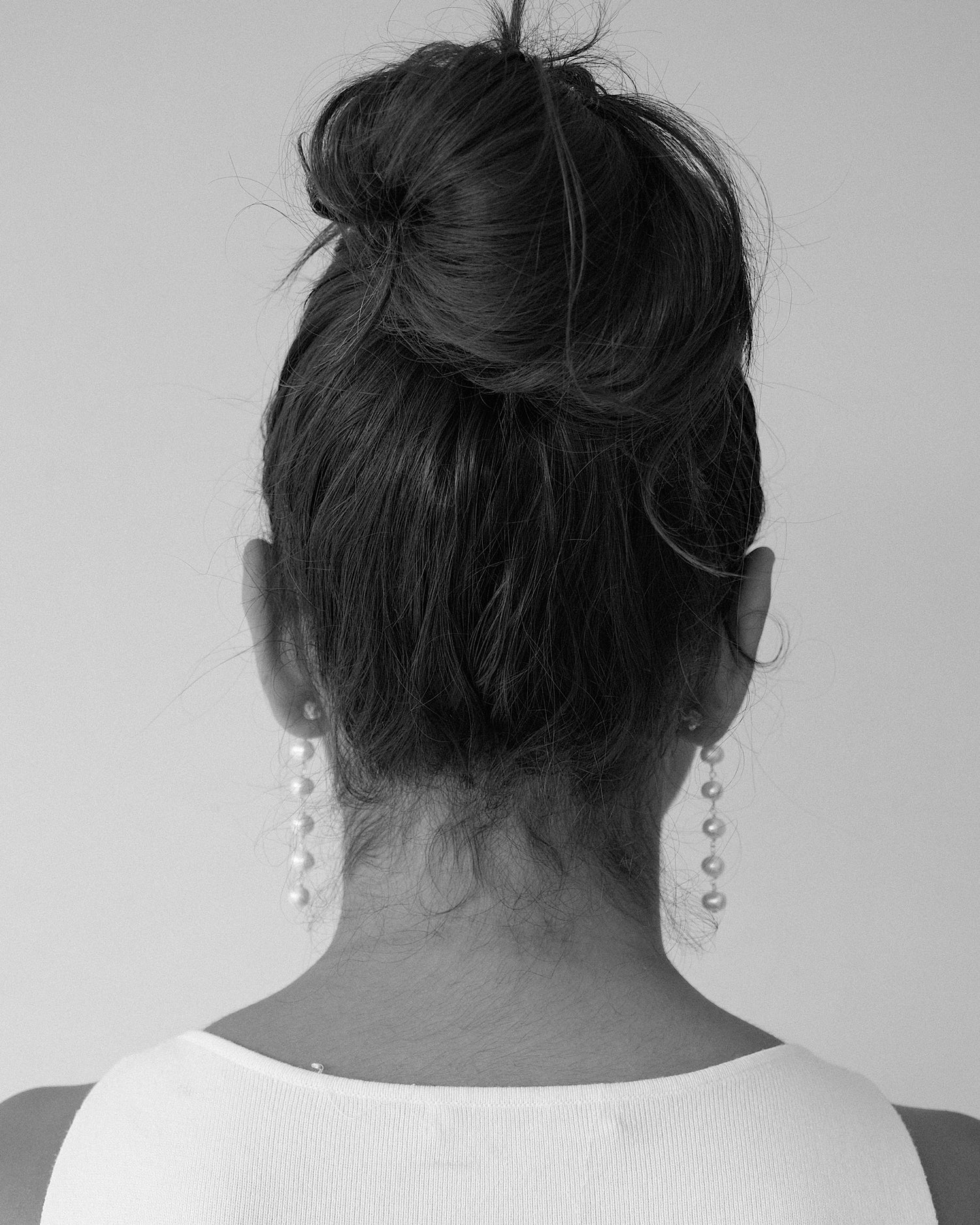 model from behind wearing long pearl earrings