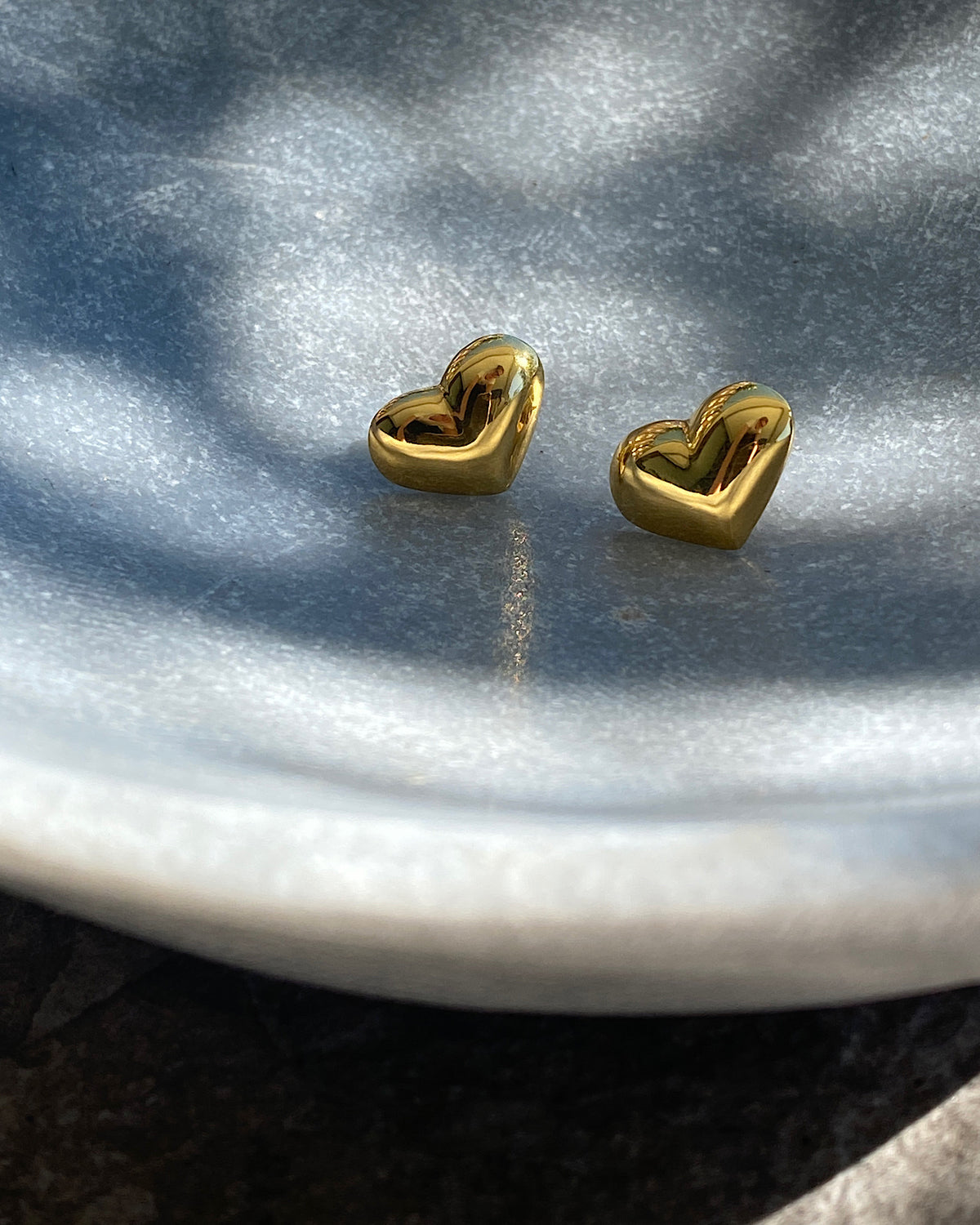 gold heart studs in a bowl