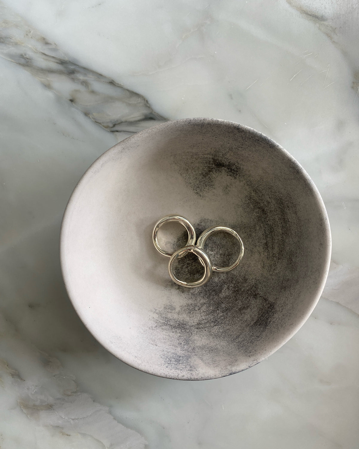 Three silver organic silver rings by Johnny Ramli sit in a bowl, Available at The Pared Store, Surry Hills