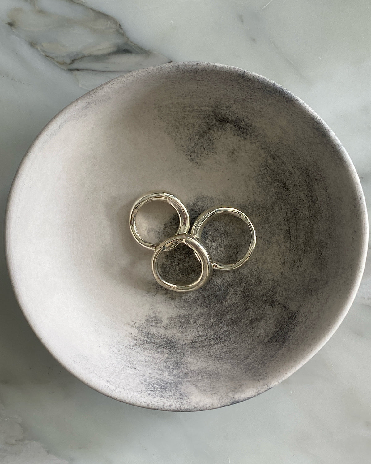 Three silver organic silver rings by Johnny Ramli sit in a bowl, Available at The Pared Store, Surry Hills