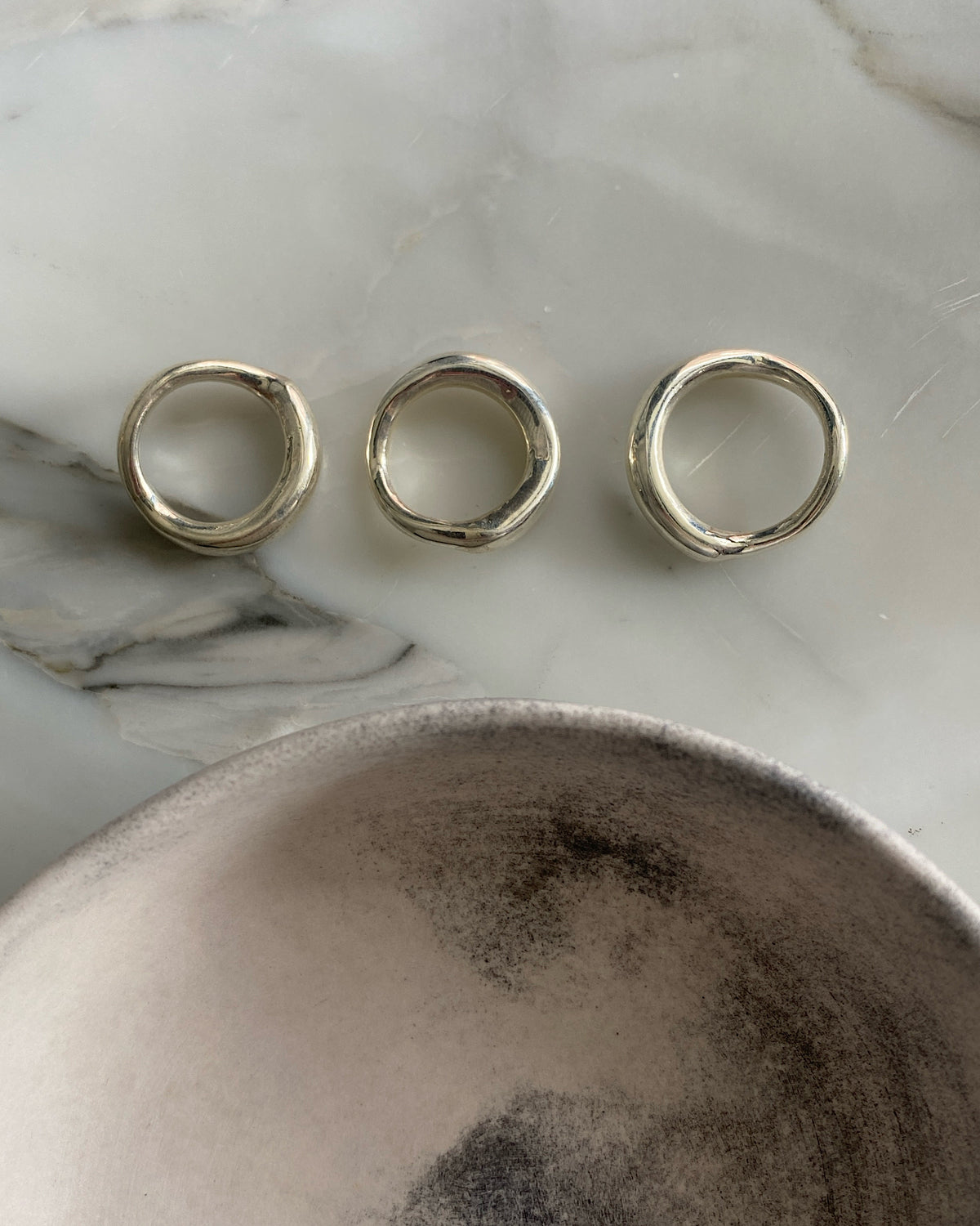 Three silver organic silver rings by Johnny Ramli sit in a bowl, Available at The Pared Store, Surry Hills