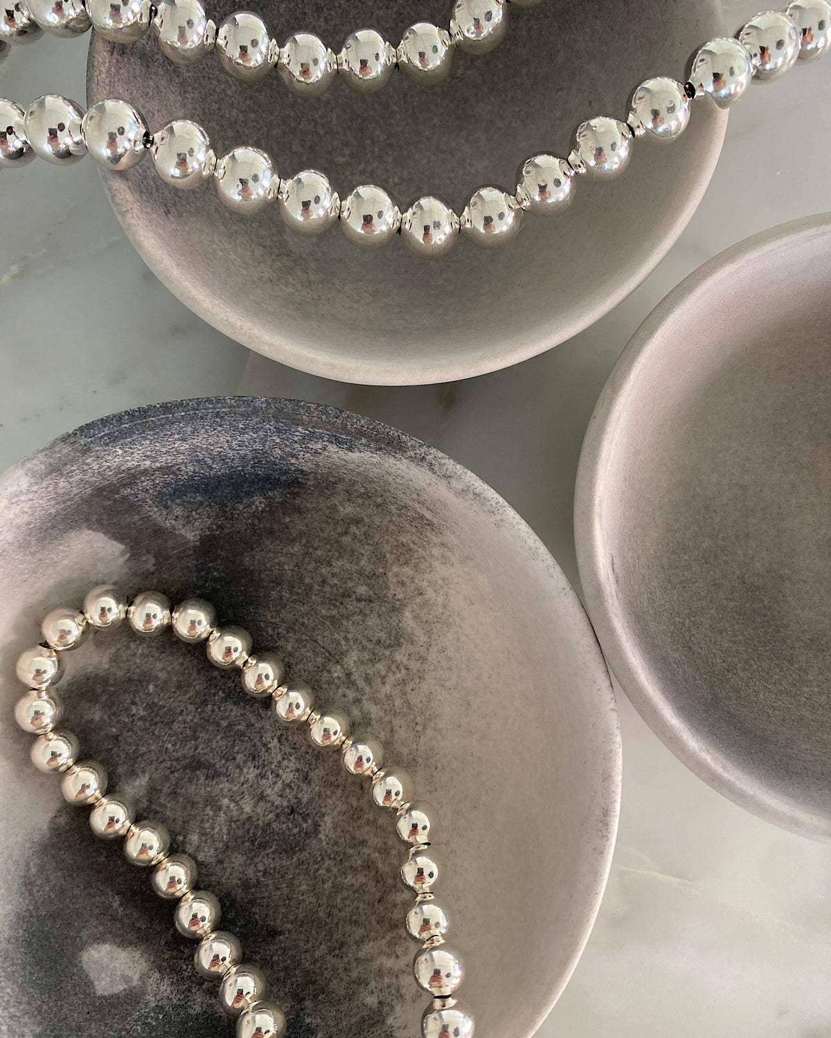 silver ball chain necklaces lie in bowls