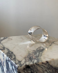 a super wide open sterling silver cuff bracelet sits on a marble plinth