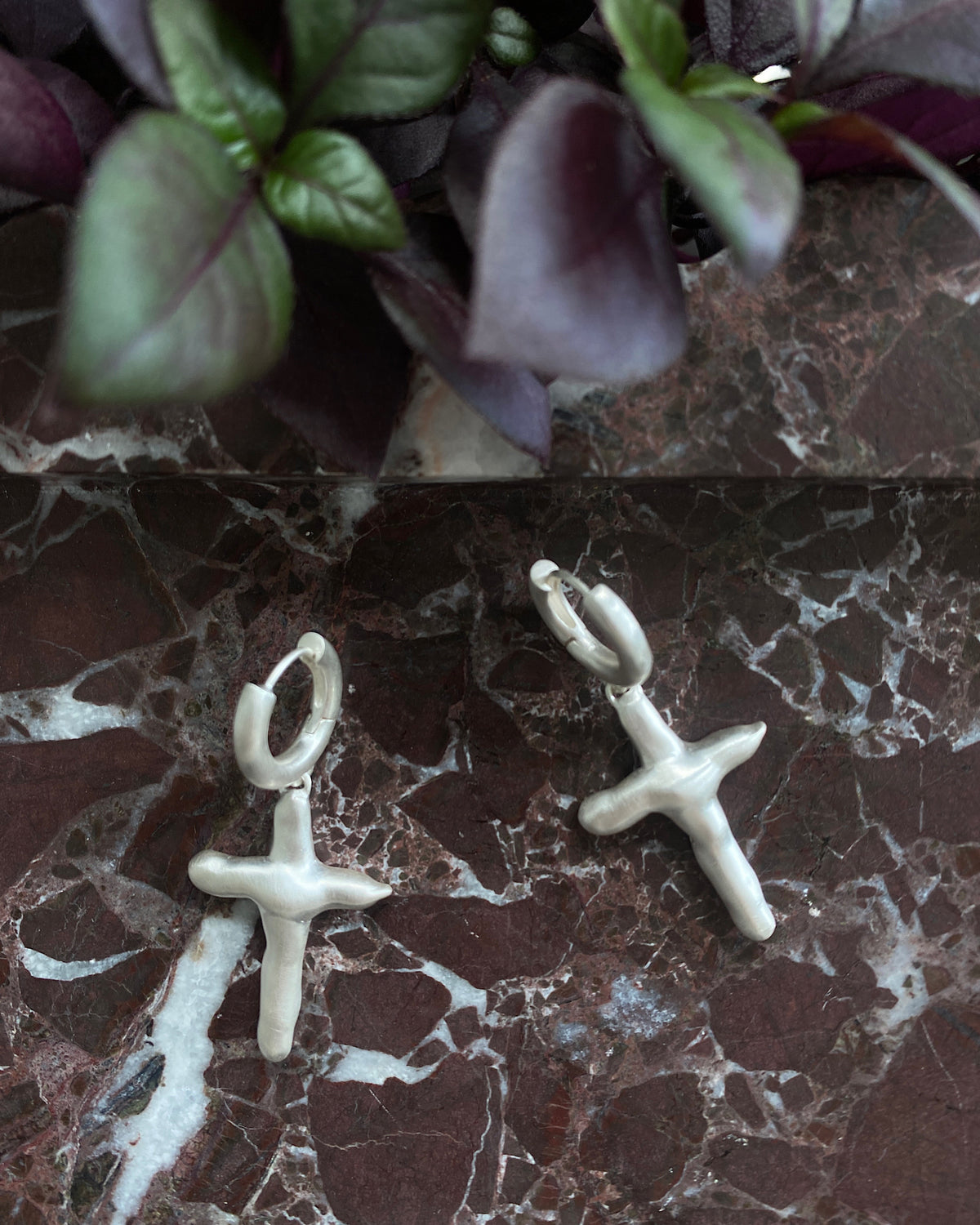 Matt silver organic cross charms suspended on a huggie style earring