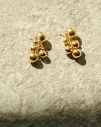 small gold bubble earrings on concrete