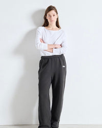Person wearing a white long-sleeve top and dark gray sweatpants against a white background