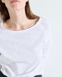 Person wearing a white long-sleeve shirt against a plain background