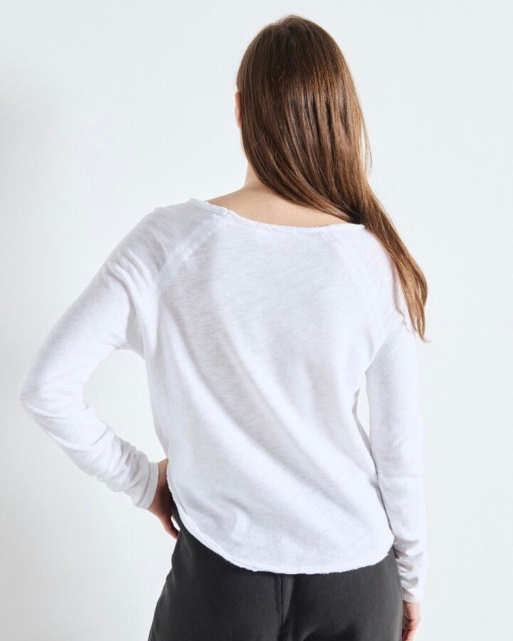 Person wearing a white long-sleeve shirt against a plain background