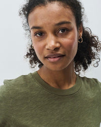 Woman wearing a green t-shirt against a plain background