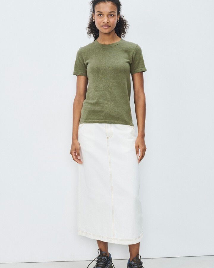 Person wearing a green t-shirt and white skirt on a white background