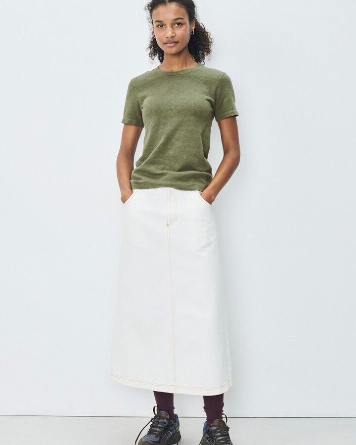 Person wearing a green t-shirt and white skirt on a white background