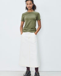 Person wearing a green t-shirt and white skirt on a white background