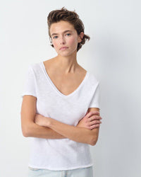 Woman wearing a white American  Vintage V-neck shirt against a plain background