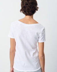 Person wearing a plain white t-shirt on a light gray background