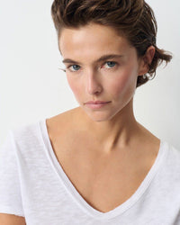 Woman wearing a white American Vintage V-neck T-shirt against a plain background