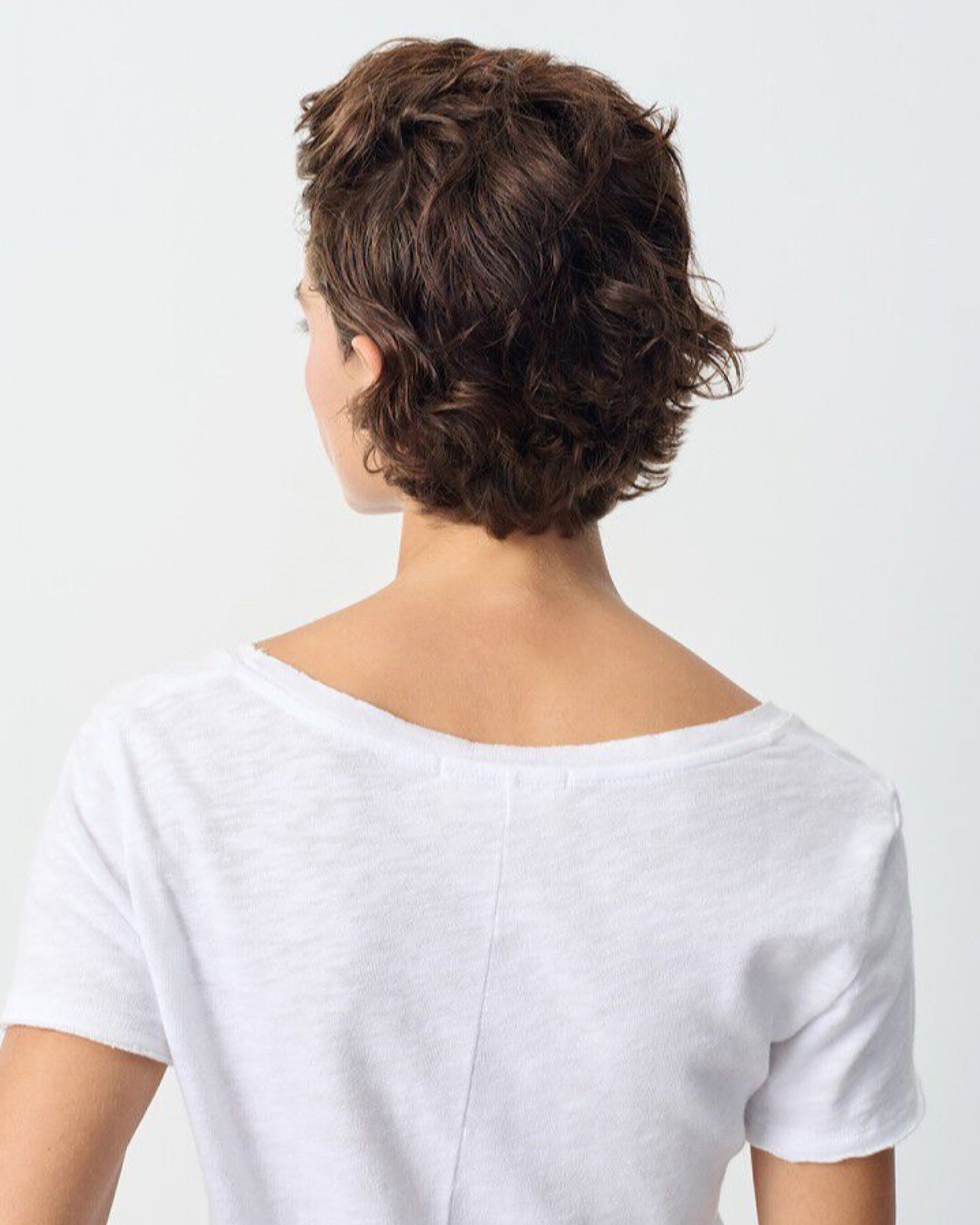 Person wearing a white shirt with a plain background