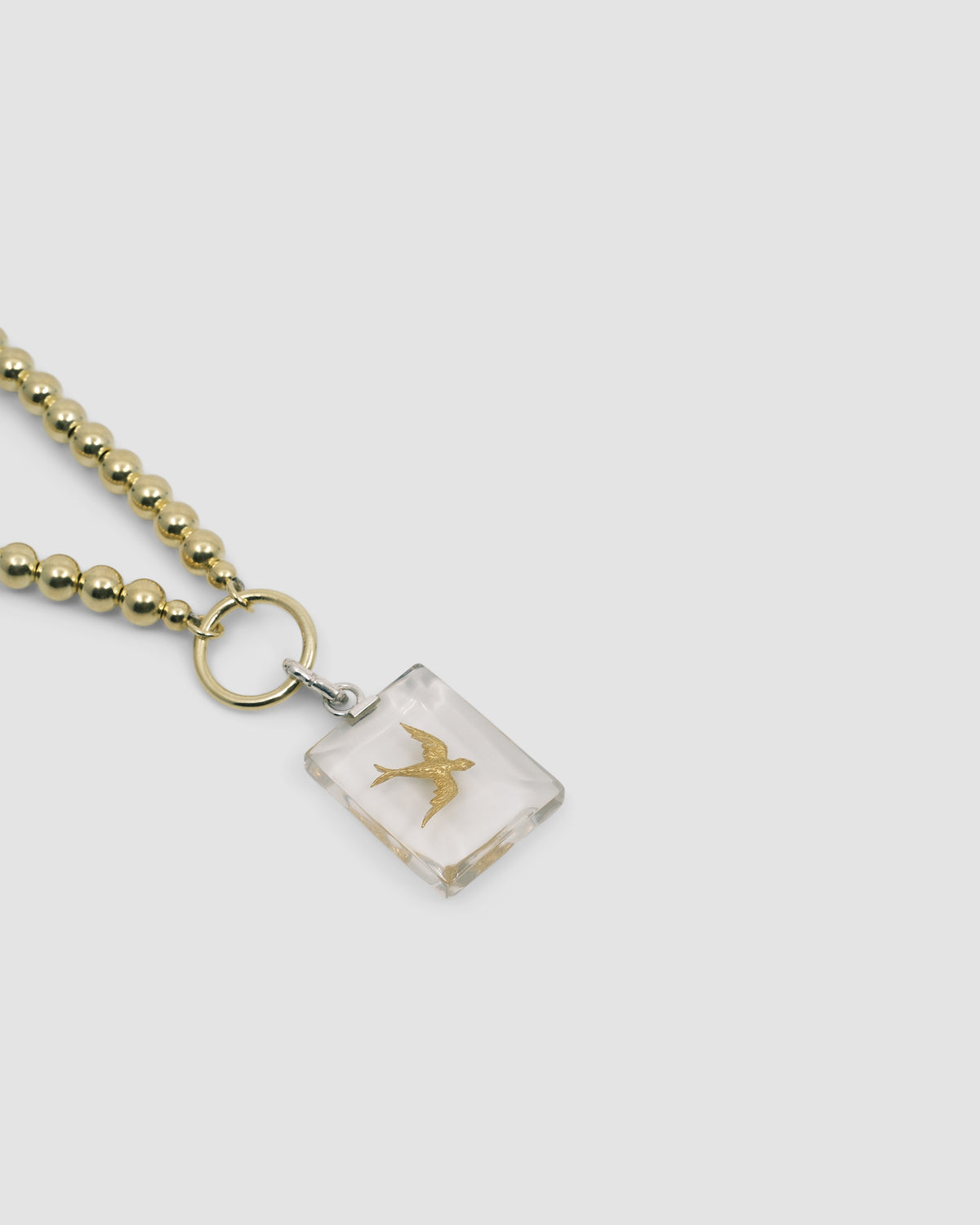 a gold ball chain with a central ring and attached bird charm