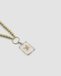 a gold ball chain with a central ring and attached bird charm