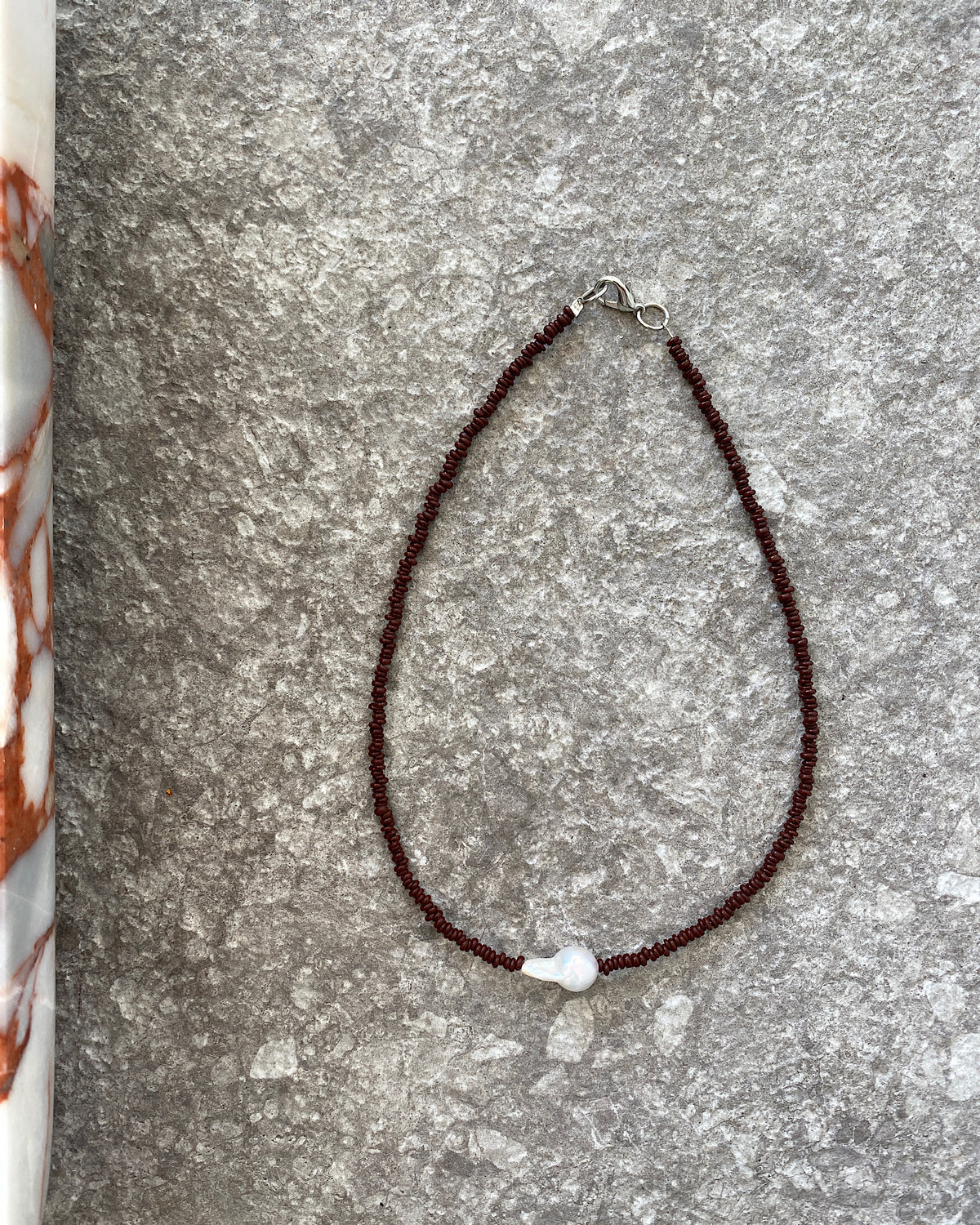 a simple baroque pearl sits on a chocolate beaded necklace