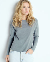 Woman wearing a blue grey long-sleeve boat neck top from American Vinatge against a white background