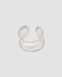 a super wide open sterling silver cuff bracelet sits on a marble plinth