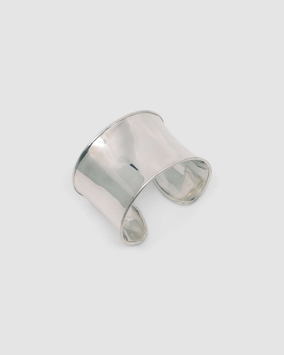 a super wide open sterling silver cuff bracelet sits on a marble plinth